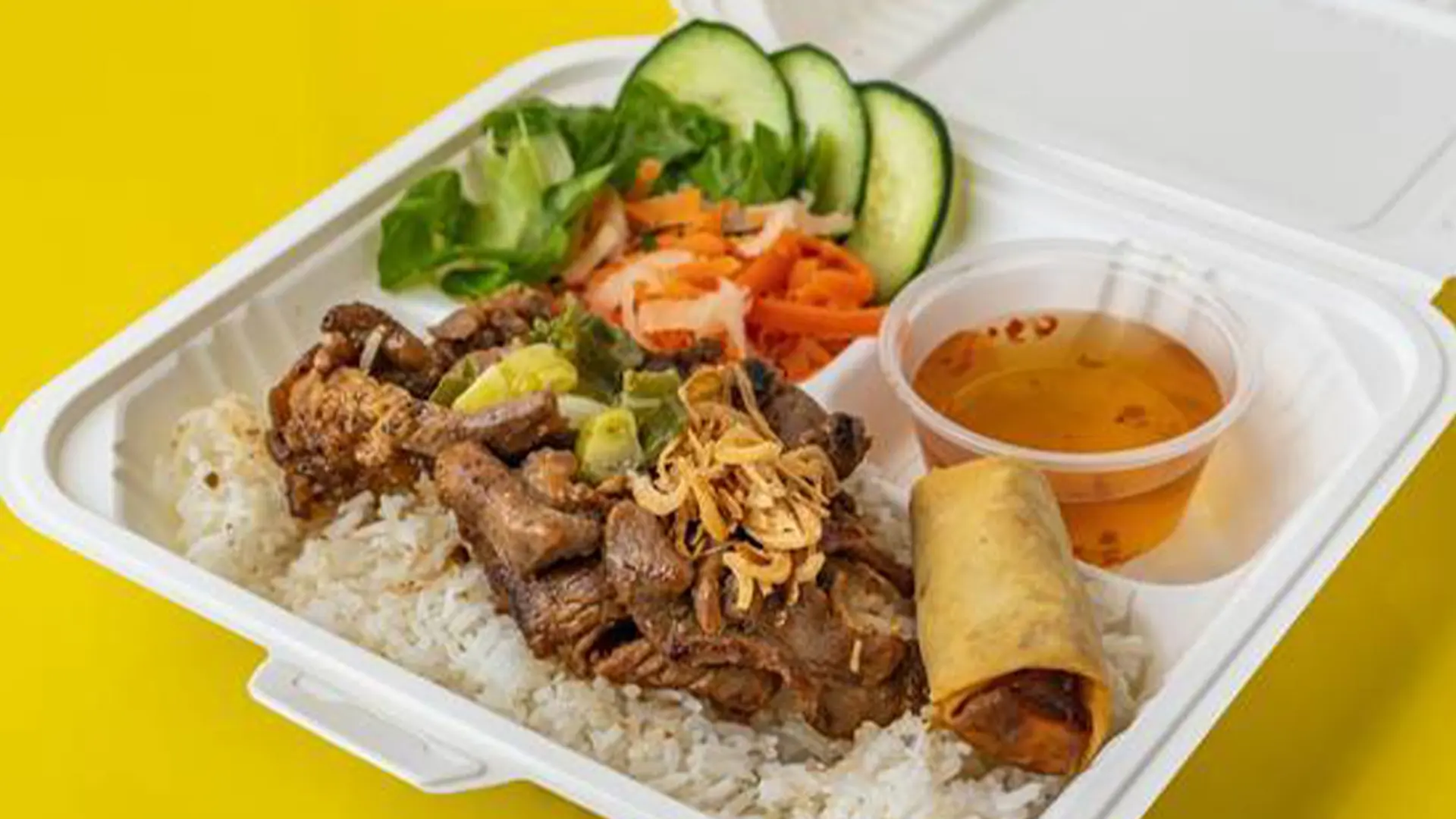 Grilled pork over rice, veggies, egg roll at Big Boss Banh Mi, a Vietnamese Restaurant in Houston